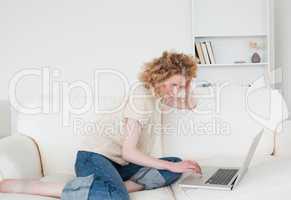 Pretty blonde woman relaxing with her laptop while sitting on a