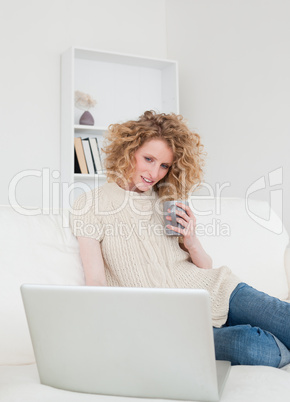 Gorgeous blonde woman relaxing with her laptop while sitting on