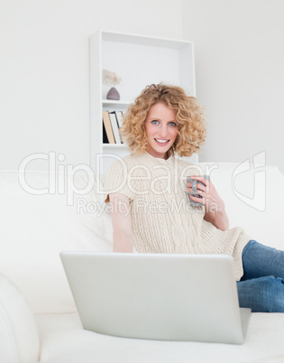 Lovely blonde woman relaxing with her laptop while sitting on a