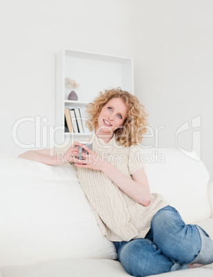 Beautiful blonde female enjoying a cup of coffee while sitting o