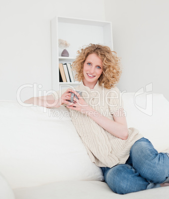 Gorgeous blonde female enjoying a cup of coffee while sitting on