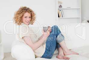 Lovely blonde female enjoying a cup of coffee while sitting on a