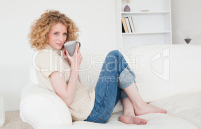 Cute blonde female enjoying a cup of coffee while sitting on a s