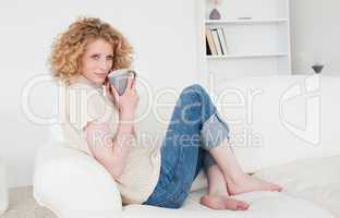 Cute blonde female enjoying a cup of coffee while sitting on a s