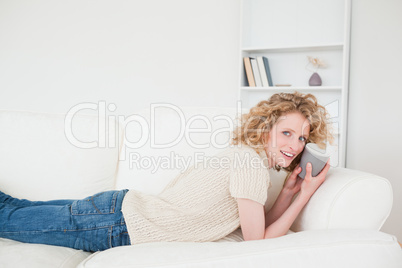 Good looking blonde woman enjoying a cup of coffee while lying o