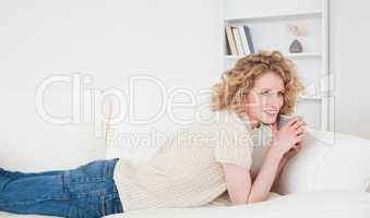 Attractive blonde woman enjoying a cup of coffee while lying on