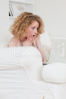 Cheerful blonde woman relaxing with her laptop while sitting on