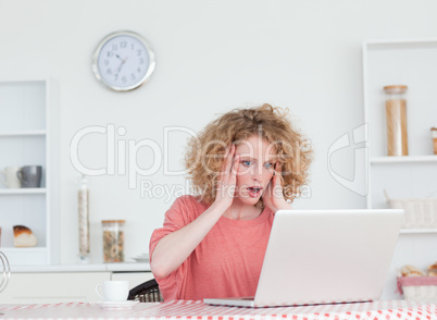 Gorgeous blonde female relaxing with her laptop while sitting in