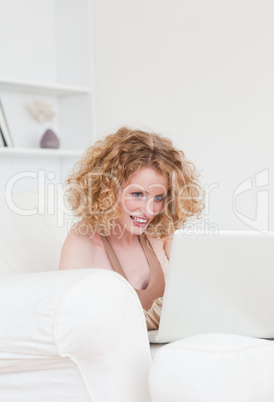 Charming blonde female relaxing with her laptop while sitting on