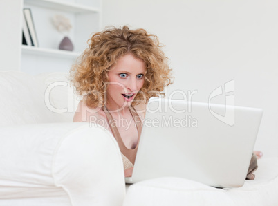 Lovely surprised female relaxing with her laptop while sitting o