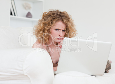 Upset blonde female relaxing with her laptop while sitting on a