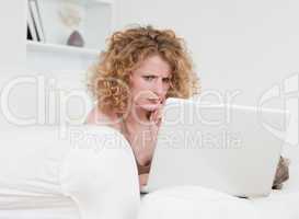 Upset blonde female relaxing with her laptop while sitting on a