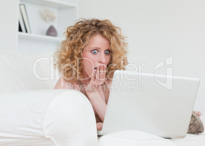 Beautiful surprised female relaxing with her laptop while sittin