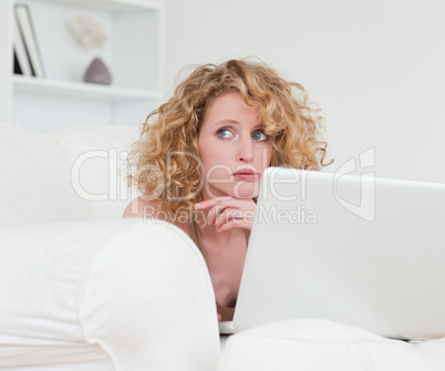 Lovely anxious female relaxing with her laptop while sitting on