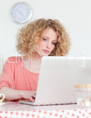 Attractive blonde woman relaxing with her laptop while sitting i