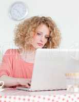 Attractive blonde woman relaxing with her laptop while sitting i