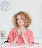 Pretty blonde woman drinking a cup of coffee while sitting in th