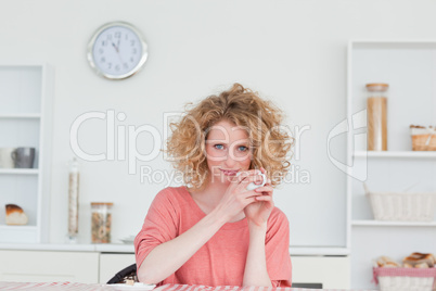 Good looking blonde woman drinking a cup of coffee while sitting