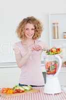 Charming blonde woman using a mixer in the kitchen
