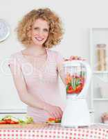 Pretty blonde woman using a mixer in the kitchen