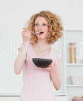 Pretty blonde woman eating a bowl of cereals in the kitchen