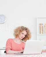 Pretty blonde woman relaxing with her laptop while sitting in th