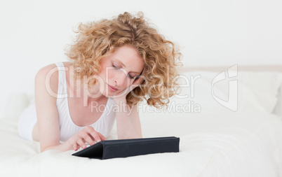 Beautiful blonde woman relaxing with her tablet while lying on a