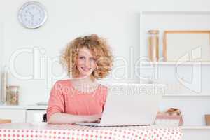 Lovely blonde woman relaxing with her laptop while sitting in th