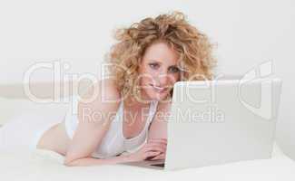 Good looking blonde woman relaxing with her laptop while lying o