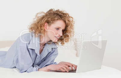 Gorgeous blonde woman relaxing with her laptop while lying on he