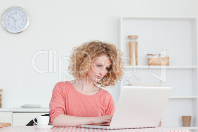 Cute blonde woman relaxing with her laptop while sitting in the