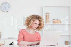 Cute blonde woman relaxing with her laptop while sitting in the