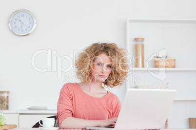 Pretty blonde woman relaxing with her laptop while sitting in th