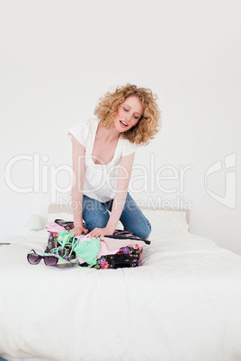 Charming blonde woman trying to close her suitcase in her bedroo