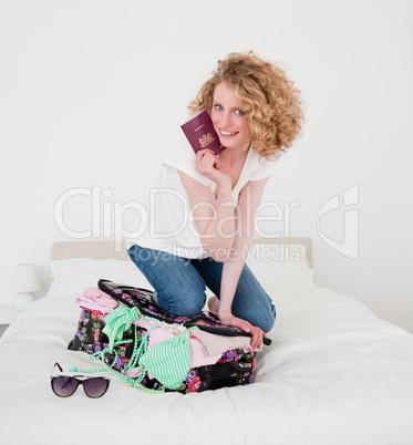 Lovely blonde woman trying to close her suitcase in her bedroom