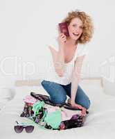 Cute blonde woman trying to close her suitcase in her bedroom