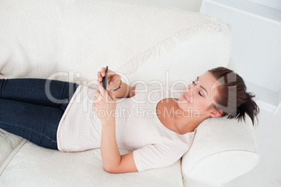 Young brunette texting while lying on her sofa