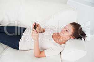 Young brunette texting while lying on her sofa