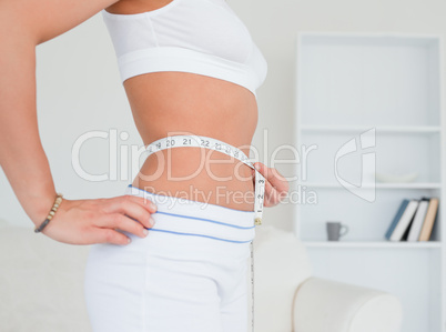 Thin young woman measuring her belly