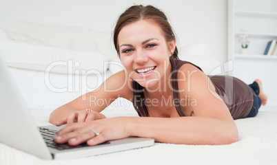 Brunette lying on a carpet with a laptop