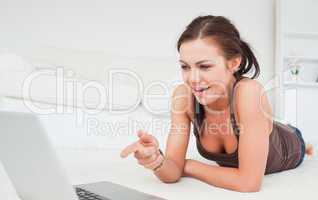 Cute woman pointing at the screen of her laptop