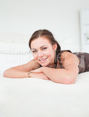 Portrait of a smiling brunette liying on a carpet
