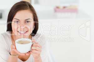Smiling dark-haired woman having a coffee