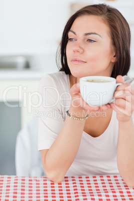 Portrait of a smiling dark-haired woman having a coffee