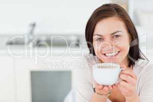 Close up of a smiling brunette having a coffee