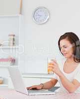 Portrait of a woman using her laptop and drinking juice