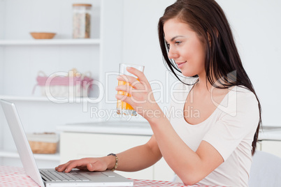 Close up of a woman using her laptop and drinking juice