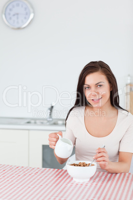 Portrait of a young woman pouring milk in her cereal