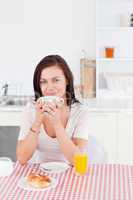 Smiling brunette having her breakfast