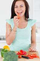 Portrait of a smiling woman eating a slice of pepper